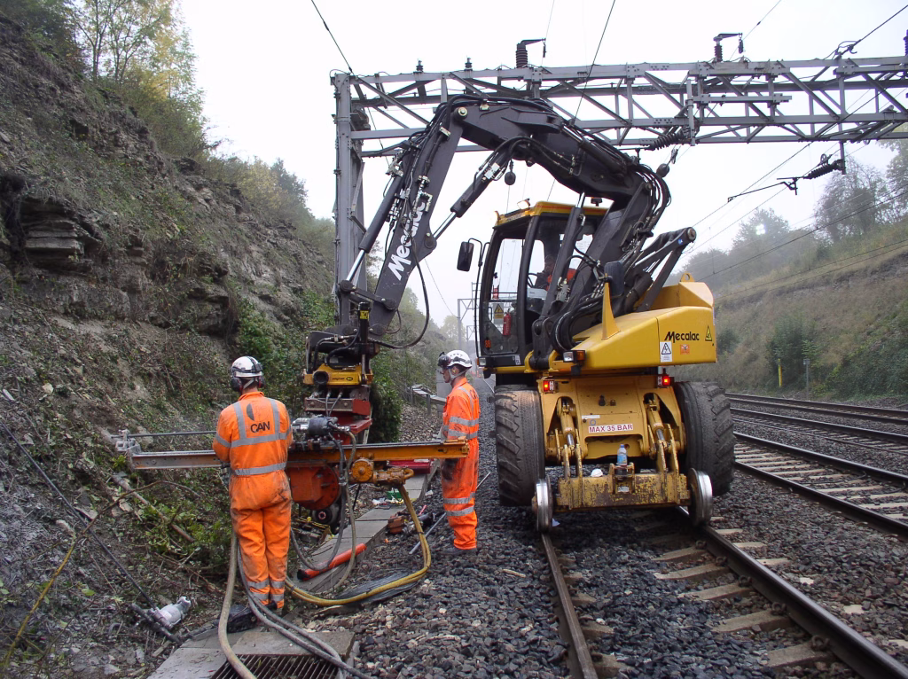 Workers in CAN uniform using heavy machinery with a nailing machine.