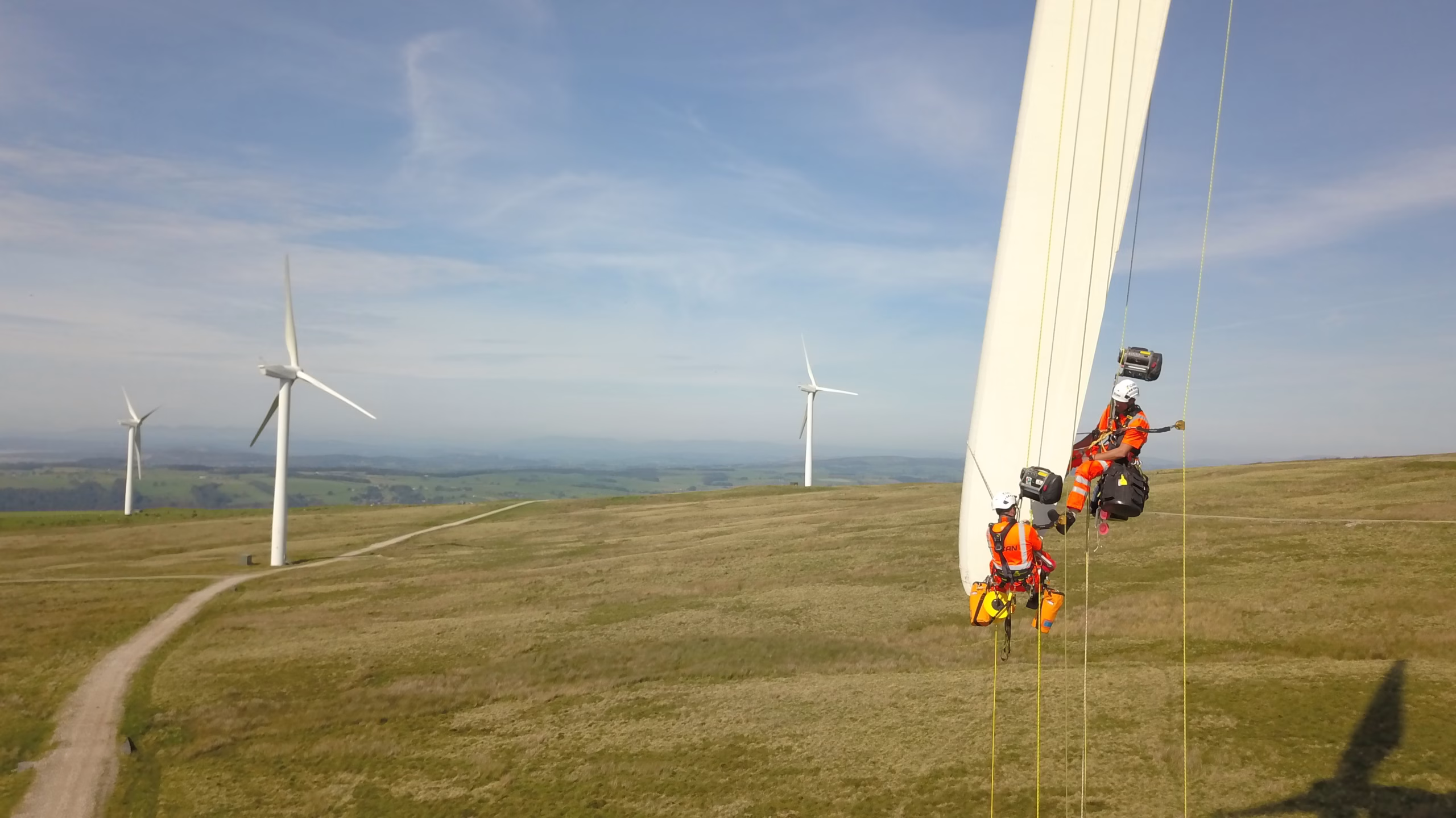 Workers on the end of a wind turbine